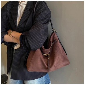 Dettaglio borsa tote in pelle scamosciata marrone con cinturino e fibbia in metallo