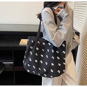 Close-up of a large black canvas tote bag featuring white number prints on a shoulder strap