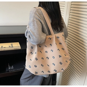 Detail of beige canvas tote bag with black number prints shown in a library setting