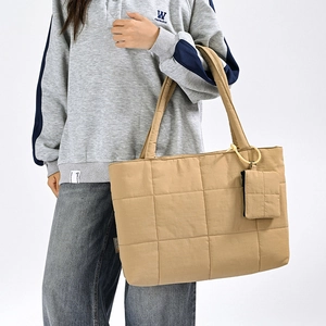 Macro detail of khaki quilted tote bag with matching small coin pouch on straps