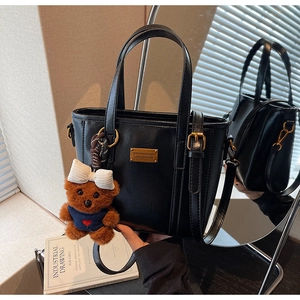 Detailed shot of black leather bucket bag with gold hardware and a cute bear charm