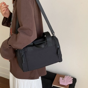 Dettaglio della borsa a tracolla in nylon nero con tasche laterali e spallina larga
