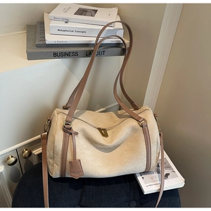 Dettaglio borsa cilindrica in camoscio beige con cinturini marroni e cerniere dorate