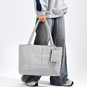 Detail of grey quilted puffer tote bag featuring a matching small accessory pouch