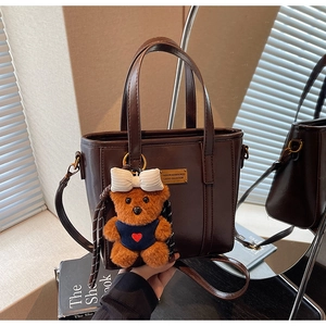 Close-up of a vintage brown bucket bag with a cute bear charm and metal logo detail