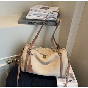 Dettaglio borsa a cilindro beige opaco con cerniere dorate e tracolla marrone