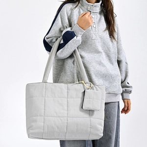 Detail of light grey quilted tote bag with matching mini purse on white background