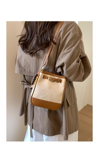 Detailed side view of minimalist bucket bag with contrast trim and wooden bead charm
