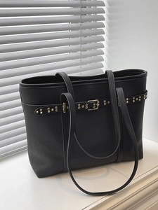 Minimalist black lychee leather tote bag with gold rivet accents and long shoulder straps