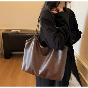 Detail of dark brown tote bag with metal chain strap and luxury leather texture