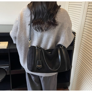 Detailed view of the black crossbody bag showing its textured fabric and brand tag