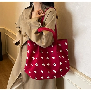 Detail of red canvas tote bag with white number print shown with classic trench coat