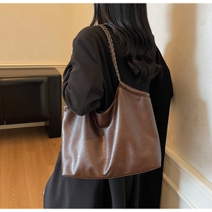 Detail of dark brown tote bag with glossy PU leather texture and chain shoulder strap
