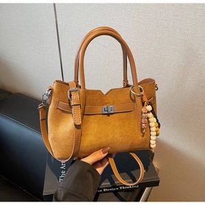 Détail du sac seau en daim camel avec boucle métallique et breloque en perles colorées