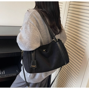 Dettaglio della borsa Boston in camoscio nero con finiture in pelle e logo vintage