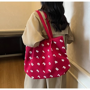 Detail of red canvas tote bag with white digit prints worn over a beige trench coat