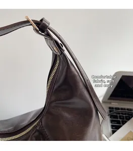 Detailansicht der glatten dunkelbraunen Ledertasche mit goldener Hardware und weichem Stoff