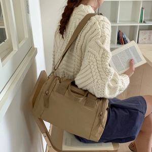 Dettaglio borsa tote in nylon kaki con tracolla larga e tasca laterale con zip su modella