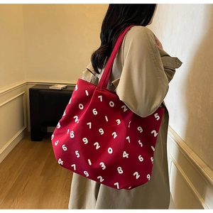 Side view of red canvas tote bag with white number prints on a model in a warm interior
