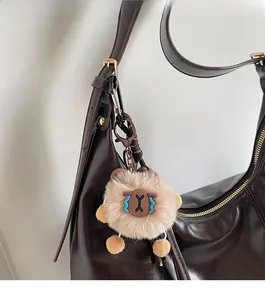 Nahaufnahme eines braunen Plüsch-Anhängers auf einer Vintage Leder-Umhängetasche für Damen