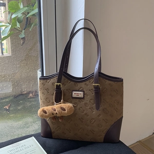 Macro view of brown suede tote bag with cat embossed patterns and bread plush charm