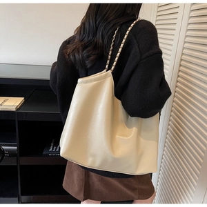 Detail of beige hobo shoulder bag with chain strap and glossy leather texture