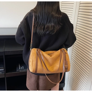 Dettaglio della borsa tote in pelle scamosciata marrone con tracolla su modella