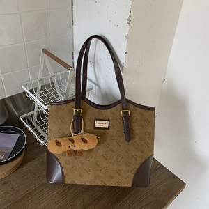 Detail of Bread Cat tote bag featuring cat pattern prints and a brown plush bread charm