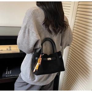 Détail du sac seau en daim noir avec fermoir tournant en métal et breloque perlée colorée