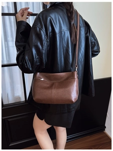 Détail d'un grand sac cabas en cuir marron porté par un mannequin en veste noire