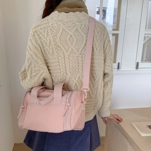 Dettaglio della borsa Boston in nylon rosa con tracolla larga regolabile indossata da modella