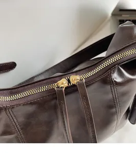 Detailansicht der glatten goldenen Doppel-Reißverschlüsse an der dunkelbraunen Vintage-Tasche