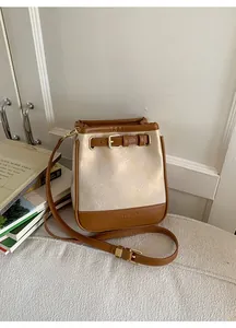Close-up of contrast patchwork bucket bag with gold crinkle texture and brown leather strap
