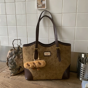 Detail shot of brown tote bag with Bread Cat embossing and plush bread charm pendant