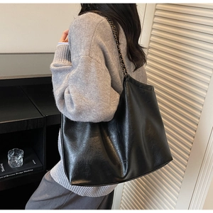 Detail of glossy vintage leather tote with black and gold woven chain shoulder strap