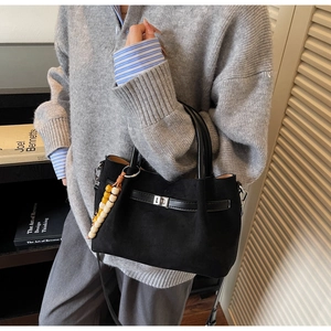 Détail du sac seau en daim noir avec fermoir argenté et breloque perlée colorée