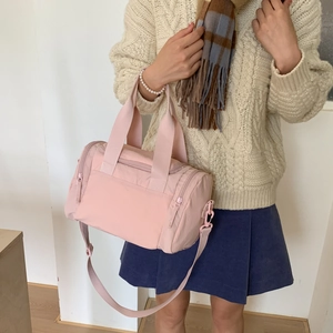 Vista dettagliata della borsa da viaggio in nylon rosa chiaro con tracolla indossata