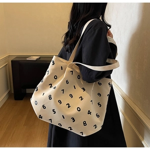 Minimalist canvas tote bag with black digital print shown on a model in a home setting