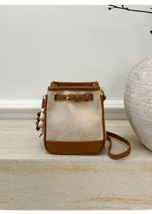 Detail of canvas bucket bag with contrast leather trim and beaded tassel charm