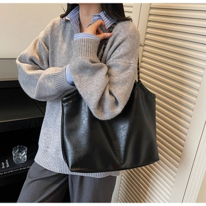 Close-up of black leather tote bag with stylish metal chain strap for daily commute