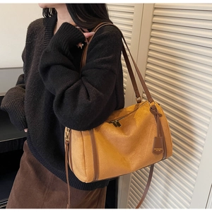 Dettaglio della borsa boston in pelle scamosciata senape con spalline in pelle marrone