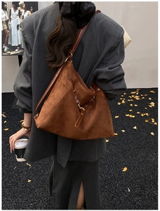 Dettaglio di una borsa tote grande in camoscio marrone con tracolla in pelle in autunno