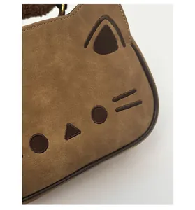 Détails de broderie chat et texture daim mat sur un sac à main marron