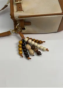 Detail view of canvas bucket bag with multicolor wood bead charm and brown leather trim