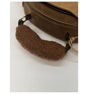 Détail du sac en daim marron avec poignée douce en peau de mouton et boucles métalliques