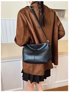 Gros plan sur un sac cabas en cuir noir avec logo de la marque et bandoulière réglable