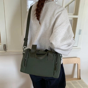 Dettaglio borsa sportiva in tela verde militare con tracolla regolabile sul modello