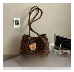 Detail of leopard print tote bag with brown plush bear charm and lifestyle accessories