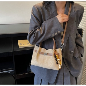 Détail du sac seau en daim beige avec garniture en cuir marron et breloque en perles