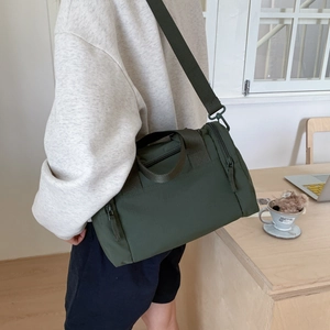 Dettaglio borsa a tracolla cilindrica in nylon verde scuro con tracolla larga e tasca laterale